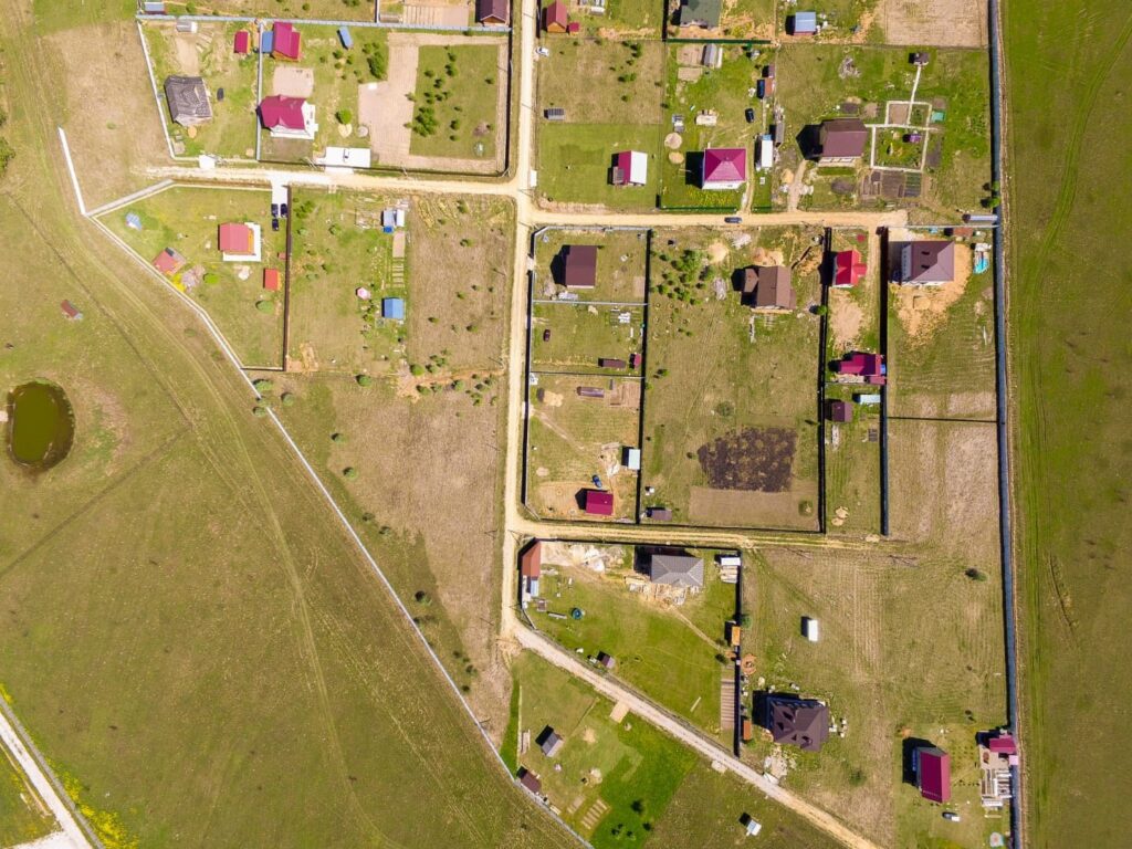 Vista aérea de loteamento rural com divisas e construções demarcadas, representando processo de retificação de área e atualização cadastral de imóveis.